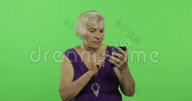 一位老年妇女在智能手机上工作。 <strong>老奶奶</strong>笑了。 铬键